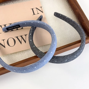 Detail showing a handmade denim polka dot headband set in blue and grey with brand labels