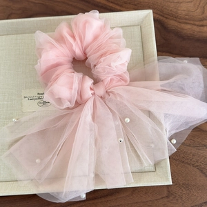 Détail d'un chouchou en résille rose clair avec longs rubans et perles blanches