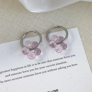 Close-up of sweet pink floral charm earrings on a minimalist decorative card