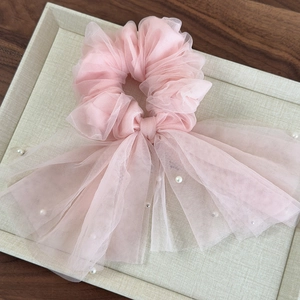 Vue détaillée du chouchou en tulle rose avec longs rubans et perles blanches élégantes