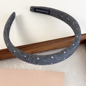 Detailed close-up of grey polka dot denim fabric headband with handmade label