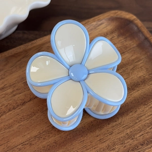 Vue macro d'une pince à cheveux fleurie crème avec bordures bleues sur bois sombre