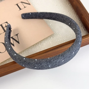 Detail view of denim headband with white polka dots on elegant textured background