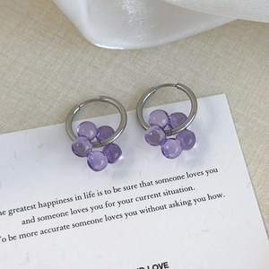 Detailed shot of silver hoop earrings featuring transparent purple beaded flower charms