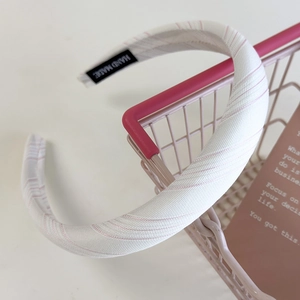 Close-up of pink striped fabric headband with handmade label on a mini cart