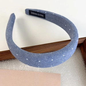 Detail of handmade denim headband with white polka dots and woven HAND MADE label