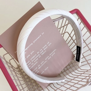 Detailed close-up of striped pink fabric headband with a woven HAND MADE logo tag