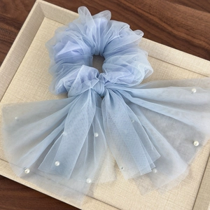 Détail d'un chouchou en tulle bleu clair avec un grand nœud et des perles blanches