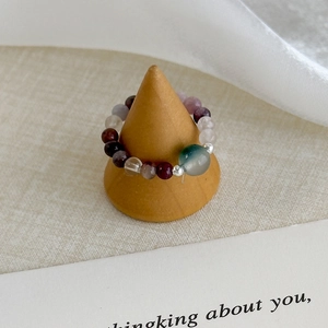 Detail of beaded natural stone ring featuring green center bead on a wooden stand