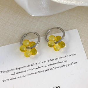 Macro shot of silver hoops with yellow resin flower charms on a decorative card