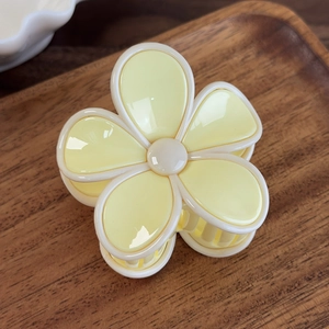 Détail d'une pince à cheveux en forme de fleur crème et jaune avec finition polie brillante