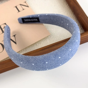 Detail of blue denim headband with white polka dots and a handmade label in a wooden tray