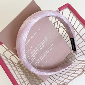 Detailed texture of light purple striped fabric headband with a black handmade label