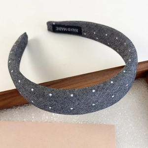 Detailed view of handmade grey polka dot headband featuring internal woven label tag