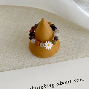 Macro shot of colorful beaded daisy ring displayed on a natural wooden jewelry stand