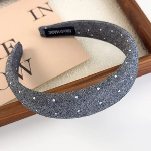 Detail of grey polka dot fabric headband featuring a handmade black interior label
