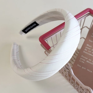 Detailed macro view of a handmade striped pink fabric headband on a decorative prop
