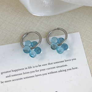 Detail of silver flower earrings with translucent blue petals on a white card