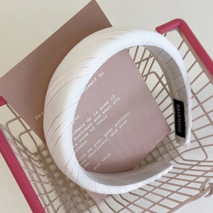 Close-up of pink striped fabric headband with handmade tag in a decorative basket