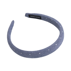 Detail of denim blue polka dot headband featuring a sewn black 'Hand Made' woven label