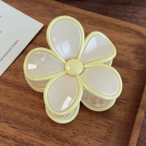 Vue détaillée de la pince à cheveux fleur crème et jaune sur un plateau en bois