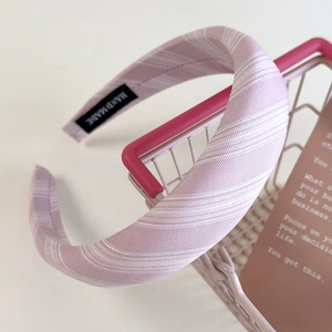 Detailed view of handmade pink striped fabric sponge headband with hand made label