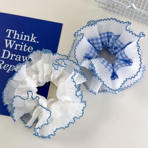 Close-up of blue plaid and white scrunchies with layered lace edges and blue stitching