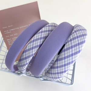 Cerchietti viola a quadretti e in tinta unita presentati in un cesto di metallo blu