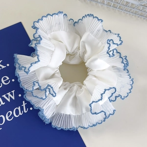Detail of blue lace trim and white satin layering on a pleated scrunchie accessory