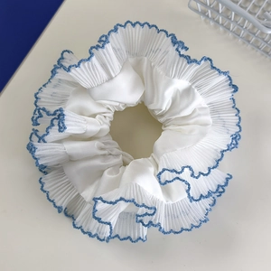 Detail of blue lace trim on a white pleated scrunchie with soft silk texture