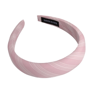 Detailed view of handmade label on pink and white striped fabric headband accessory