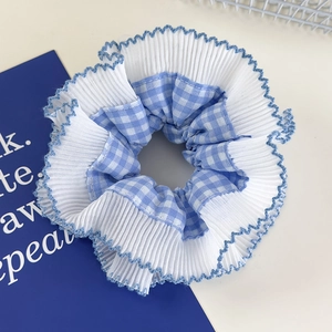 Detailed view of blue plaid scrunchie with layered white pleats and blue stitched edges
