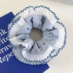 Detail of blue plaid scrunchie with double-layer white pleated lace trim hair tie