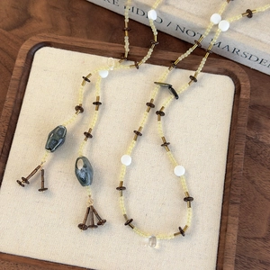 Détail d'un collier de perles vintage avec pendentifs en pierre sur un plateau