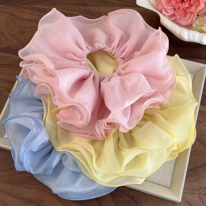 Détail de chouchous en mousseline multicouche en couleurs rose, jaune et bleu pastel