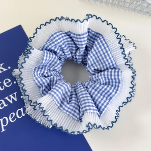 Detail of blue plaid scrunchie featuring white lace trim and ruffled fabric texture
