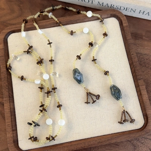 Sautoir perles bohème avec pendentifs pierre et glands vintage sur plateau en lin