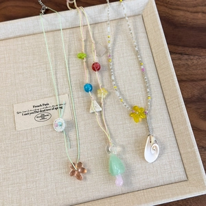 Handmade colorful beaded necklaces with mushroom and shell pendants on display tray
