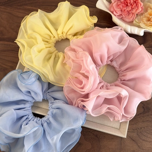 Détail de chouchous en mousseline superposée en jaune, rose et bleu avec couture fine