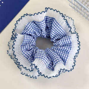 Close-up of blue plaid scrunchie with white lace trim and dark blue stitched edges