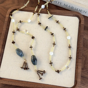 Collier ethnique avec perles, pendentifs en pierre bleue et gland sur plateau en bois