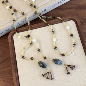 Gros plan d'un collier long perlé vintage avec pendentifs en céramique et glands