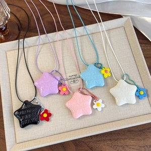 Détail de cinq pendentifs étoiles colorés avec texte gravé et breloques de fleurs