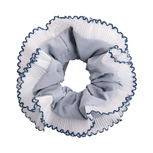 Detail of blue plaid scrunchie featuring white pleated chiffon with wavy blue stitched edges