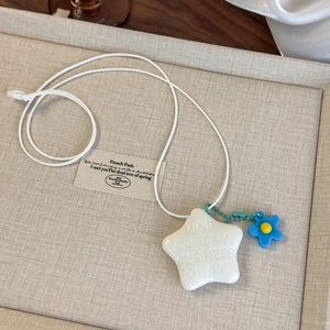 Détail du pendentif étoile blanche avec fleur bleue sur surface tissée beige doux