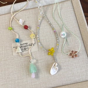 Detailed close-up of handmade colorful beaded necklaces with mushroom and shell charms