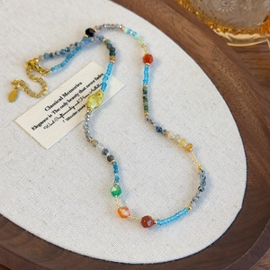 Close-up of colorful stone beads necklace with gold clasp on linen texture
