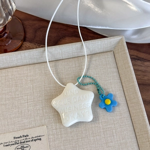 Détail du pendentif en forme d'étoile avec lettrage en relief et charm fleur bleue