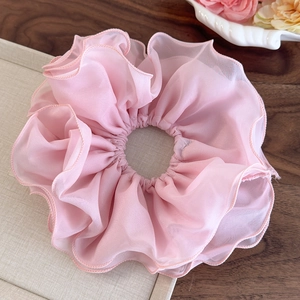 Détail d'un chouchou géant en mousseline rose avec volants et bords ondulés