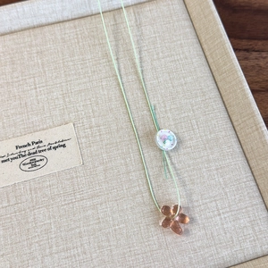 Detail of beaded necklace with orange flower pendant on a beige textured tray